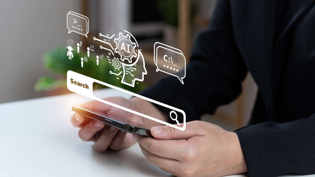 Eine Person hält ein Smartphone; darüber liegen Grafiken von KI-Symbolen und einer Suchleiste. Der Hintergrund ist unscharf.