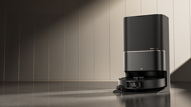 Ein schwarzer Dreame X40 Ultra Complete Saugroboter steht auf einem glänzenden Boden vor einer Wand. Links ist der Text "Dreame" zu sehen.