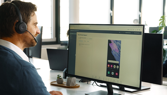 Ein Mann sitzt mit einem Headset vor seinem Computer.