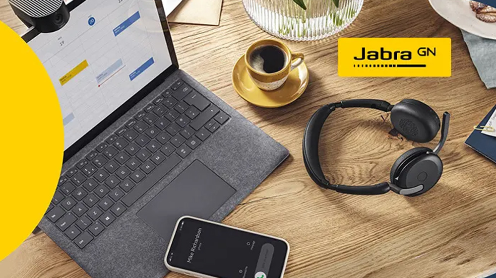 Ein Arbeits-Notebook und ein Smartphone liegen auf einem Schreibtisch. Daneben ein Headset von Jabra.