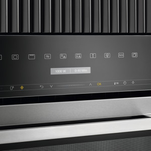 Nahaufnahme eines schwarzen Bedienfelds mit Symbolen und einer Digitalanzeige über einem silbernen Metallstreifen.