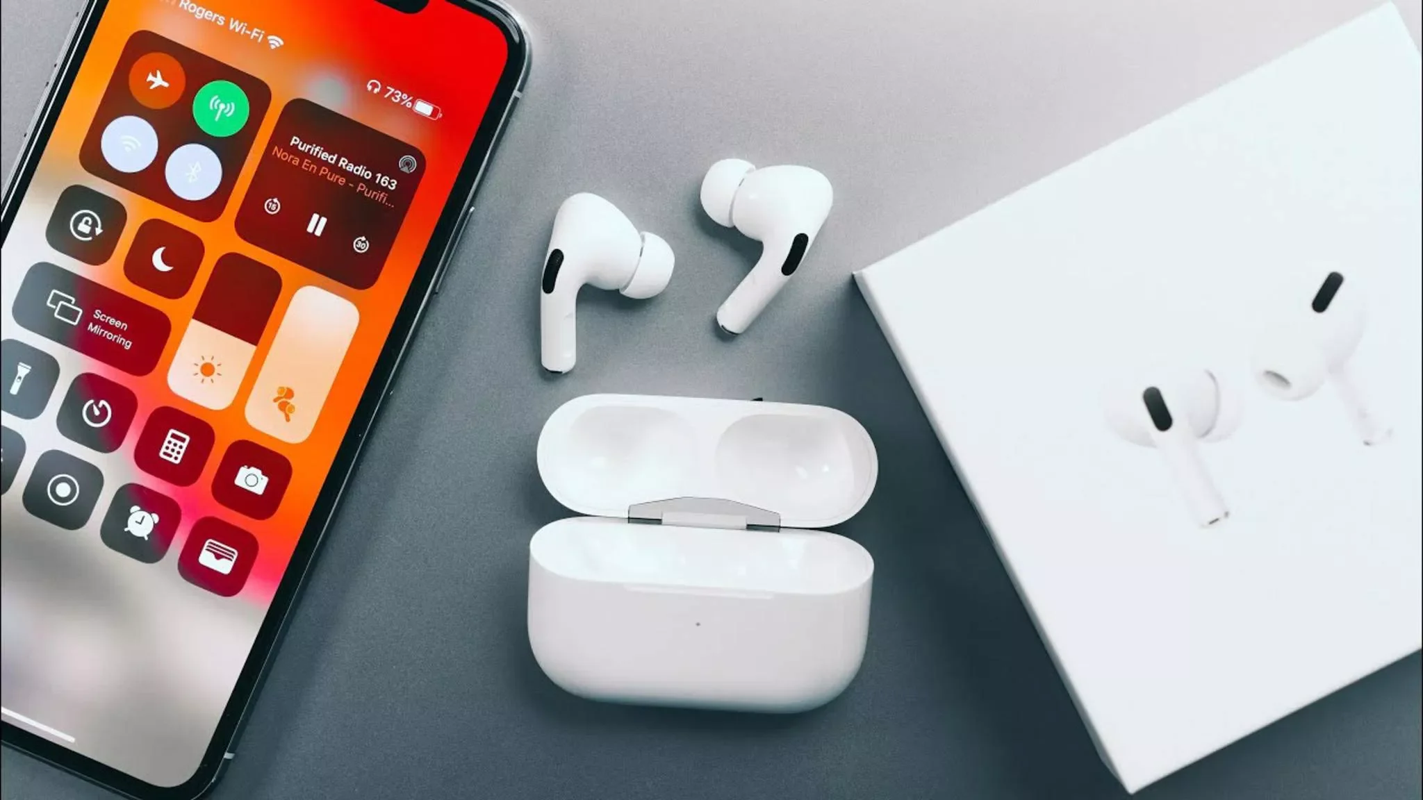 Ein iPhone und Apple AirPods mit dem Ladecase und der Verpackung liegen nebeneinander.