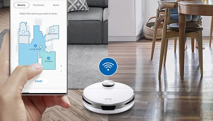 Ein Roboterstaubsauger reinigt einen Holzboden, gesteuert über eine App auf einem Smartphone in der Hand.