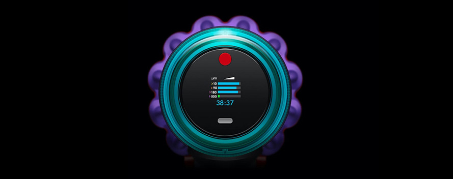 Eine Nahaufnahme eines Geräts mit einem runden Bildschirm, umgeben von einer türkisfarbenen Fassung und einem lila, strukturierten Rand. Der Bildschirm zeigt blaue Balken und Zahlen.