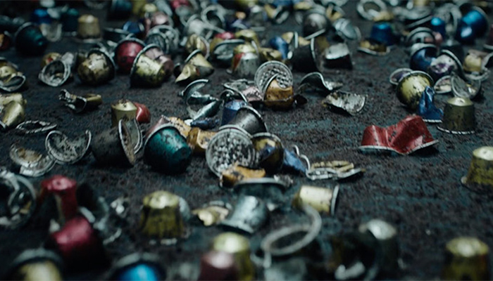 Auf dunklem Grund liegen viele gebrauchte Kaffeekapseln aus Aluminium in Blau, Rot, Gold und Silber.