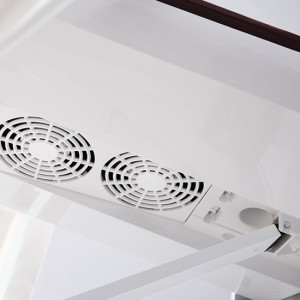 Weiße Decke mit zwei runden Lüftungsgittern und einem Drehknopf zur Steuerung der Luftzirkulation.