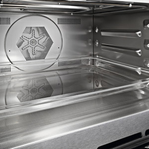 Innenansicht eines leeren, sauberen Ofens mit metallischen Innenwänden, einem Lüfter und Regaleinschüben.