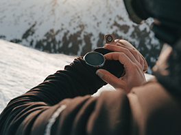 Ein Skifahrer in den Bergen sieht auf seine Smartwatch.