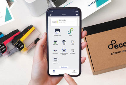 Ein Telefon zeigt eine App mit Symbolen, daneben Tintenpatronen und eine braune Schachtel mit schwarzem Text.