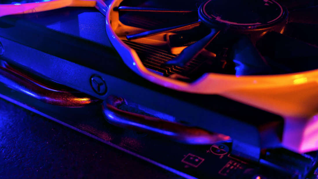 Nahaufnahme einer Grafikkarte mit Kühlkörper, Lüfter und Heatpipes in Blau- und Orangetönen.