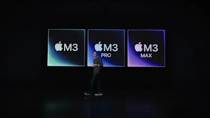 Ein Mann steht vor drei Bildschirmen mit der Aufschrift "M3", "M3 PRO" und "M3 MAX" mit Apple-Logos.