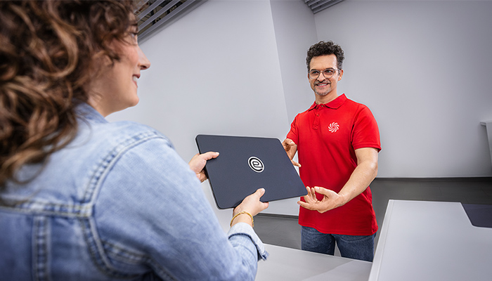 MediaMarktSaturn-Mitarbeiter nimmt ein gebrauchtes Notebook von einer Kundin entgegen.