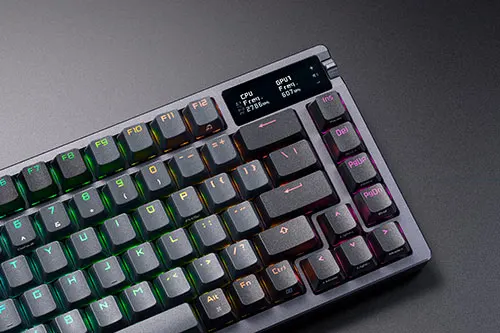 Tastiera meccanica grigia con tasti retroilluminati multicolore e display informativo in alto a destra.