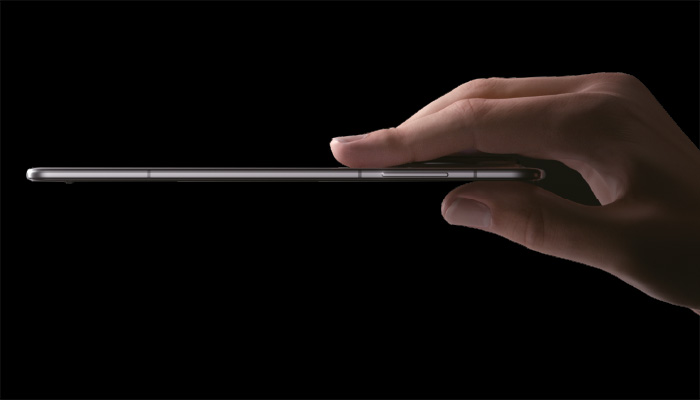 Su sfondo nero, una mano tiene un sottile dispositivo rettangolare orizzontalmente.