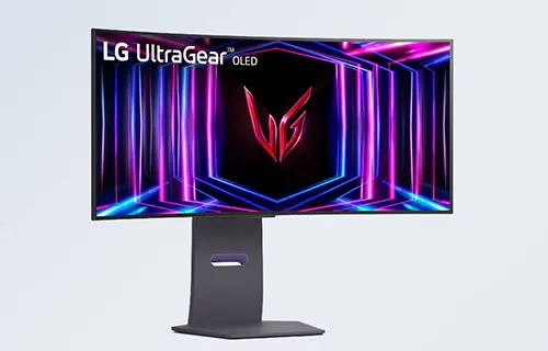 Monitor LG UltraGear OLED su supporto grigio. Lo schermo mostra un motivo geometrico blu e viola su sfondo nero.