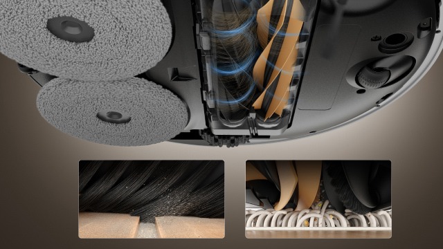 Vista dal basso di un robot aspirapolvere grigio con panni di pulizia rotondi e spazzole rotanti visibili.