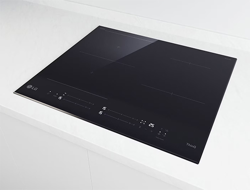 Piano cottura a induzione nero su superficie bianca, con display digitale e logo LG in basso.
