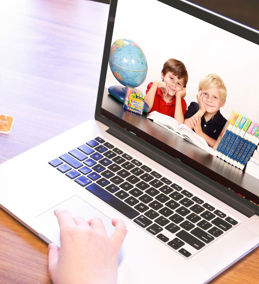 Schermo di un laptop su un tavolo di legno, con una mano che usa il trackpad. Sullo schermo, due bambini, un globo e libri.