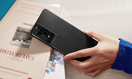 Una mano tiene un telefono nero su un libro con testo e un'immagine. Un secondo libro � in parte visibile.