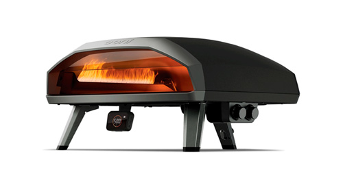 Forno per pizza nero con vetro anteriore e fuoco visibile, su gambe grigie, su sfondo bianco.