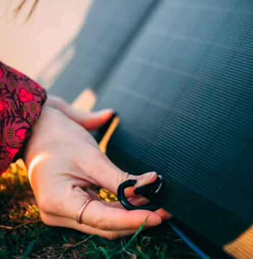 Mano che tiene un anello su pannello solare nero su erba verde.