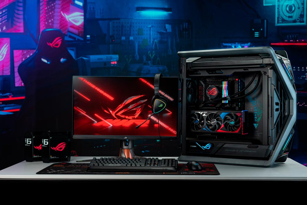 Una configurazione da gioco mostra un PC, un monitor con cuffie, tastiera e mouse su una scrivania bianca. Sullo sfondo, una sedia da gioco.