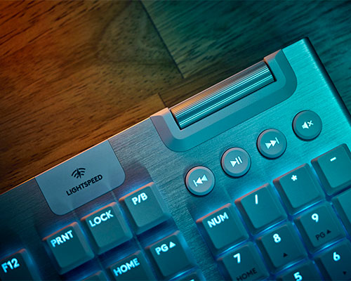 Tastiera retroilluminata su scrivania di legno. La tastiera ha tasti funzione, tastierino numerico e controlli multimediali.