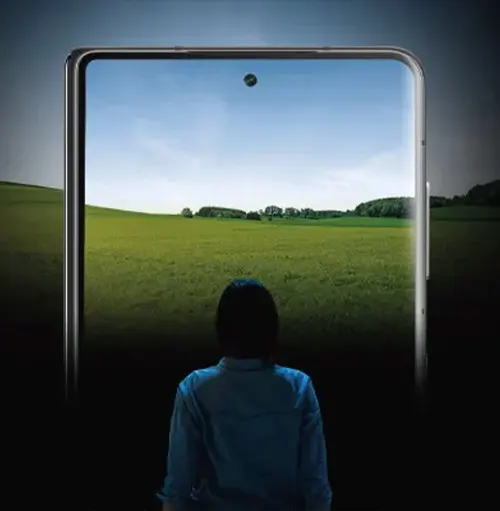 Una persona guarda uno smartphone che mostra un campo verde sotto un cielo azzurro.