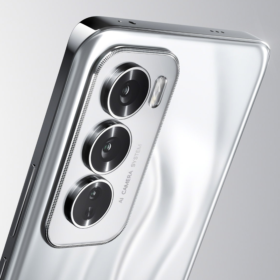 Vista angolata di smartphone argentato con tre obiettivi circolari e flash, etichettato "AI CAMERA SYSTEM".