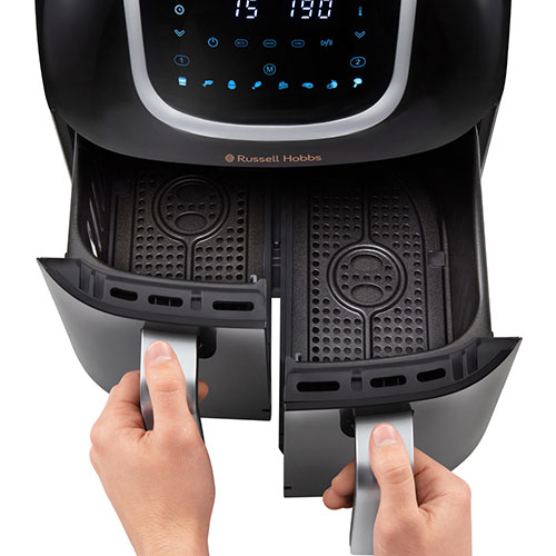 Friggitrice ad aria nera aperta da due mani che tirano le maniglie grigie dei due cestelli interni.