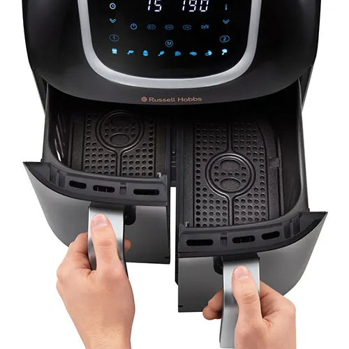 Friggitrice ad aria nera aperta da due mani che tirano le maniglie grigie dei due cestelli interni.