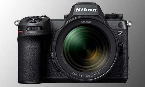 Primo piano di una fotocamera Nikon nera con obiettivo Nikkor su sfondo grigio sfumato.