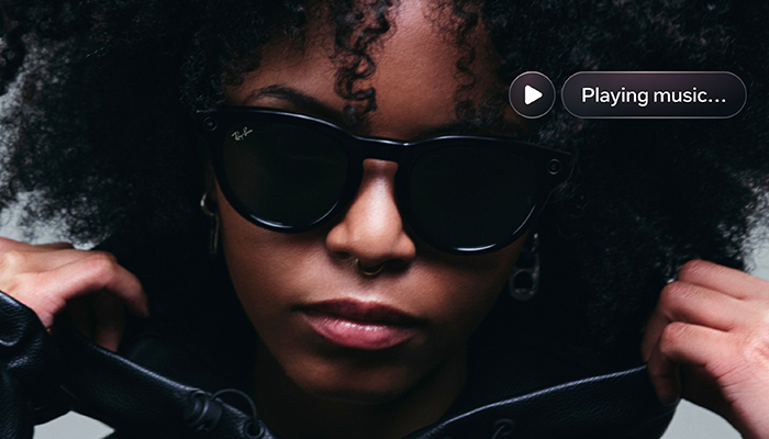 donna dai capelli ricci neri che indossa fegli occhiali ray-ban neri con un pormpt vicino "playing music"