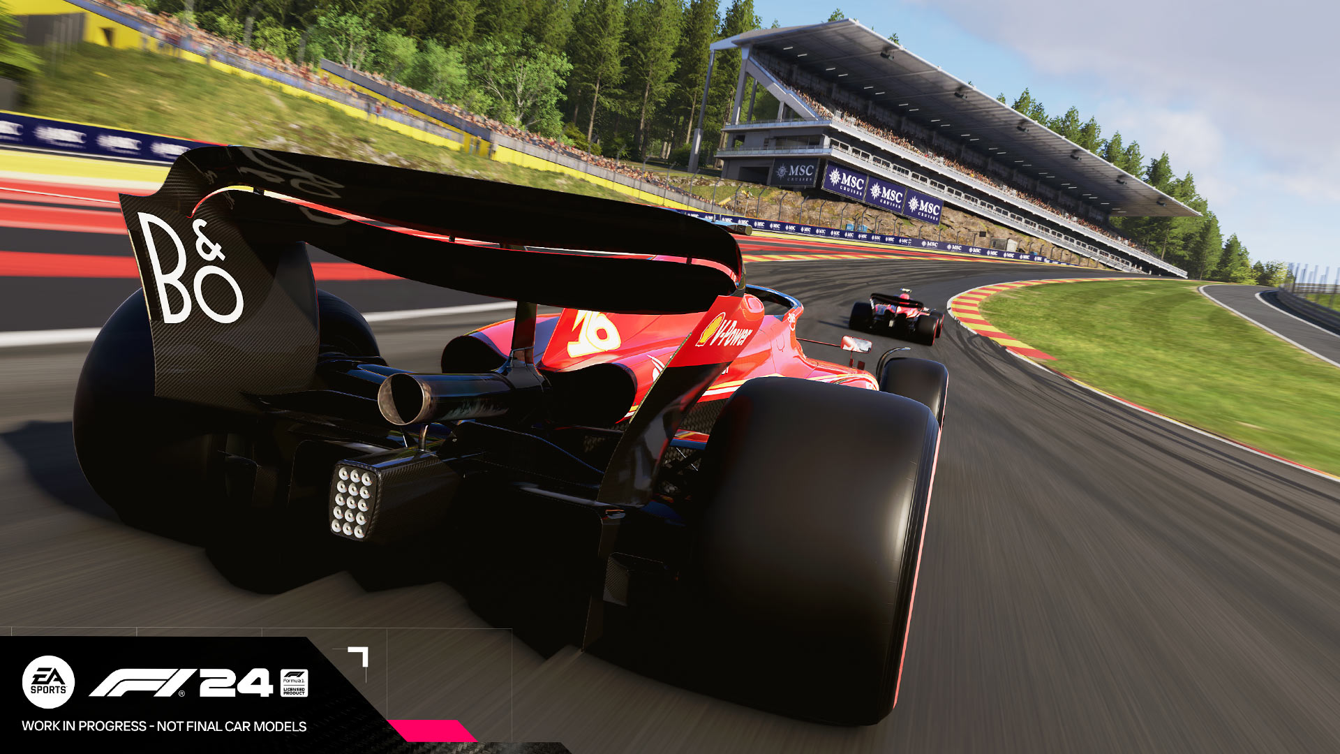 Veduta di una gara automobilistica su pista, con tribune sullo sfondo e auto rosse in primo piano.