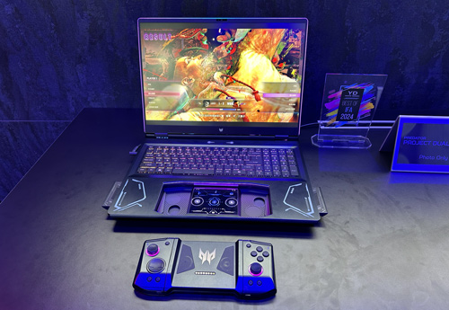 Un laptop nero aperto mostra un videogioco. Un controller di gioco è in primo piano su un tavolo nero.