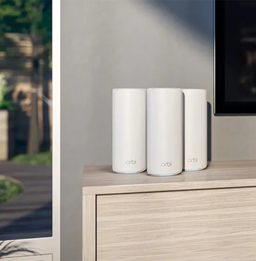 Tre cilindri bianchi su un mobile di legno chiaro, accanto a una finestra e una TV.