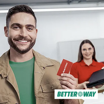 Uomo sorridente tiene carta rossa, donna in camicia rossa sullo sfondo. Logo "Better Way" in basso.