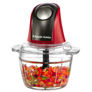 Robot da cucina rosso e nero con ciotola in vetro piena di verdure tritate.