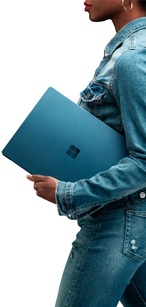 Donna in denim con laptop turchese con logo.