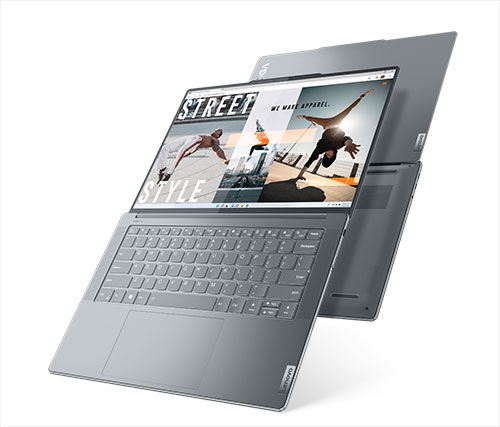 Ecco un portatile grigio aperto con una tastiera e un altro portatile grigio sullo sfondo. Lo schermo mostra immagini di persone.