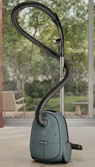 Aspirapolvere blu con tubo nero su pavimento chiaro, con finestra sullo sfondo.