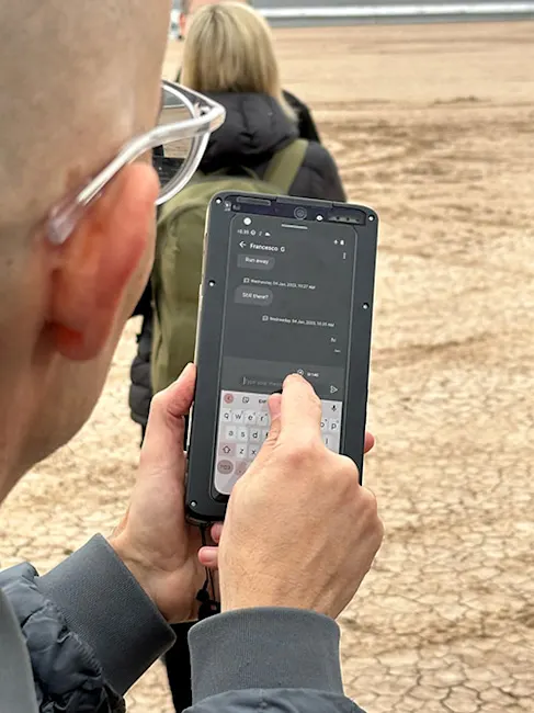 Un uomo usa un telefono con tastiera. Una persona con uno zaino � sullo sfondo.