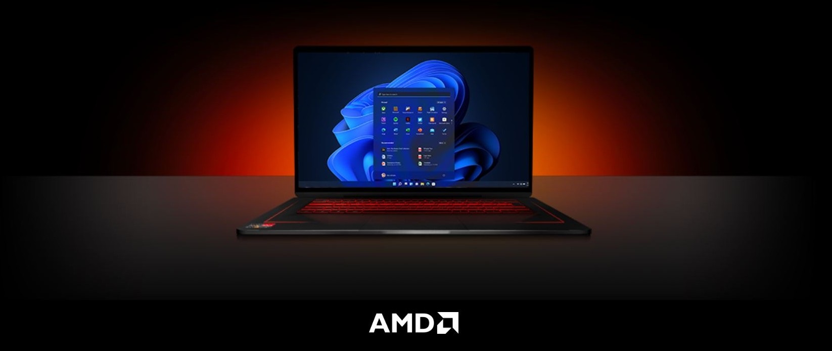 Un laptop aperto mostra lo schermo con il logo di Windows. La tastiera � illuminata di rosso. Sul fondo si legge il logo AMD.