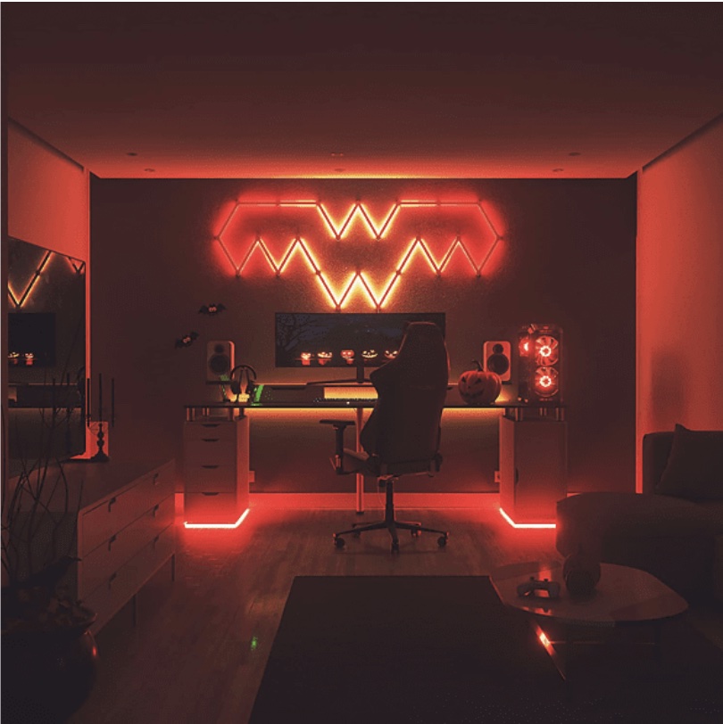 Interno illuminato di rosso con scrivania da gaming, sedia e PC. Decorazioni a tema Halloween sullo schermo e sulla scrivania.