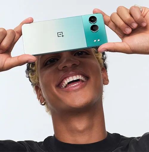 Un uomo sorridente tiene un telefono bicolore sopra la testa. Lo sfondo è bianco.