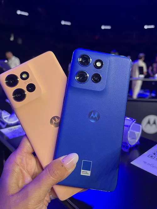 Una mano tiene due telefoni: uno blu con quattro obiettivi e uno pesca con tre obiettivi. Entrambi hanno il logo Motorola.