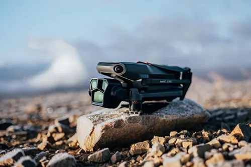 Un drone nero � appoggiato su una roccia chiara. Sfondo sfocato di rocce e cielo azzurro.