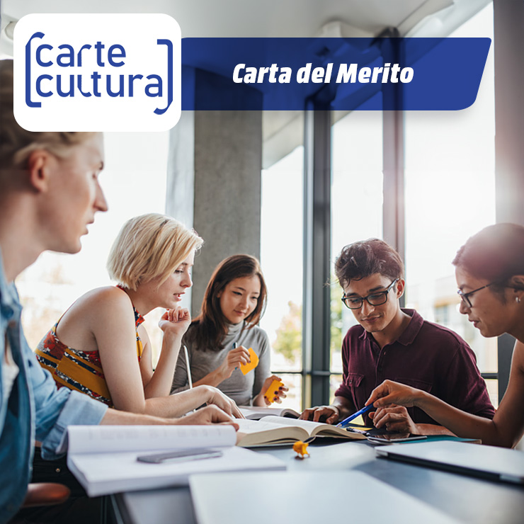 Cinque studenti siedono a un tavolo, studiano un libro aperto e prendono appunti con delle penne. Sul tavolo ci sono altri libri.