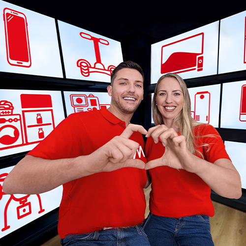 Uomo e donna sorridenti in t-shirt rosse e jeans, formano un cuore con le mani. Sfondi bianchi con oggetti rossi.