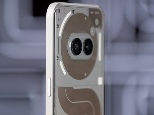 Un telefono bianco mostra due lenti nere su un cerchio marrone. Pannelli marroni e bianchi sono visibili sotto.